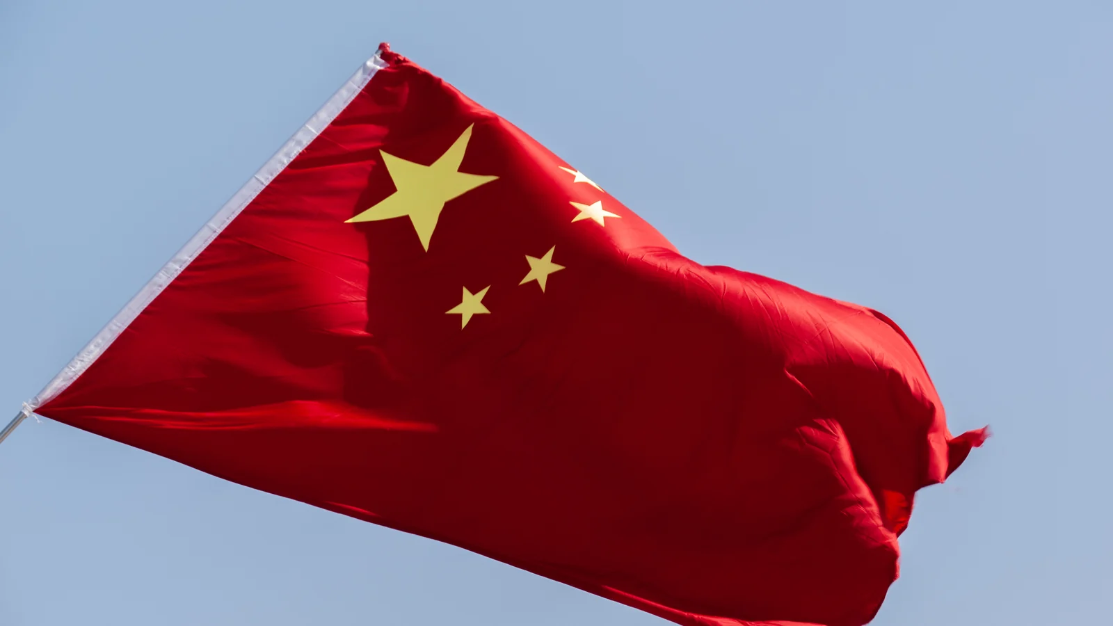 A red flag is visibly billowing against a pale blue sky.